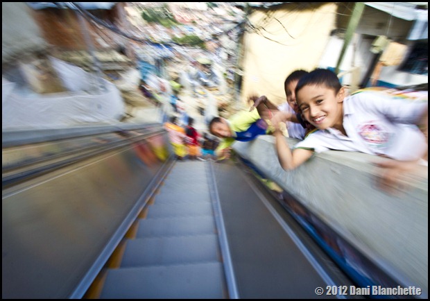 Children standing on the stairs waving. Slow shutter motion photo while riding down the escalator next to the children.