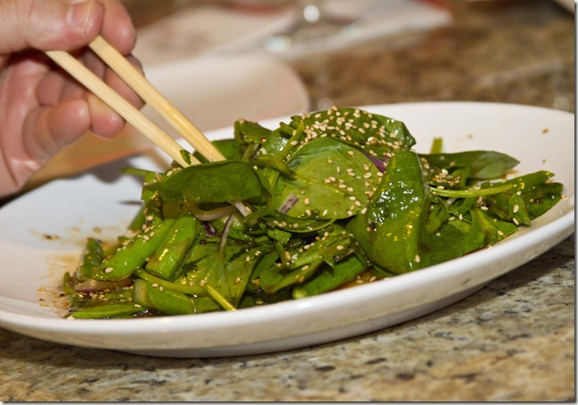spinach salad being eaten with chopsticks