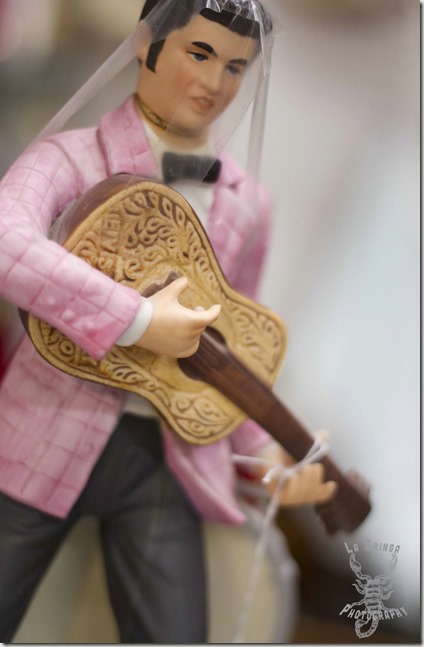 mini elvis playing guitar, statue, little statue, man in pink shirt, guitar